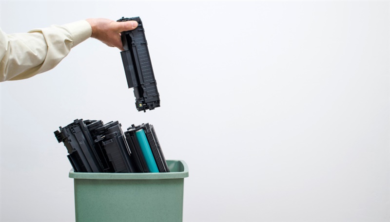 Mano con tóner que se desecha en un balde